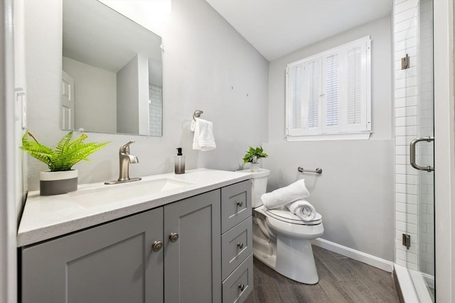 bathroom with hardwood / wood-style flooring, walk in shower, vanity, and toilet