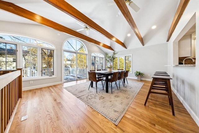 dining room with ceiling fan, light hardwood / wood-style flooring, and vaulted ceiling with beams