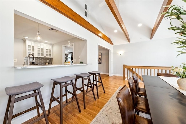 kitchen featuring pendant lighting, tasteful backsplash, kitchen peninsula, and white cabinets