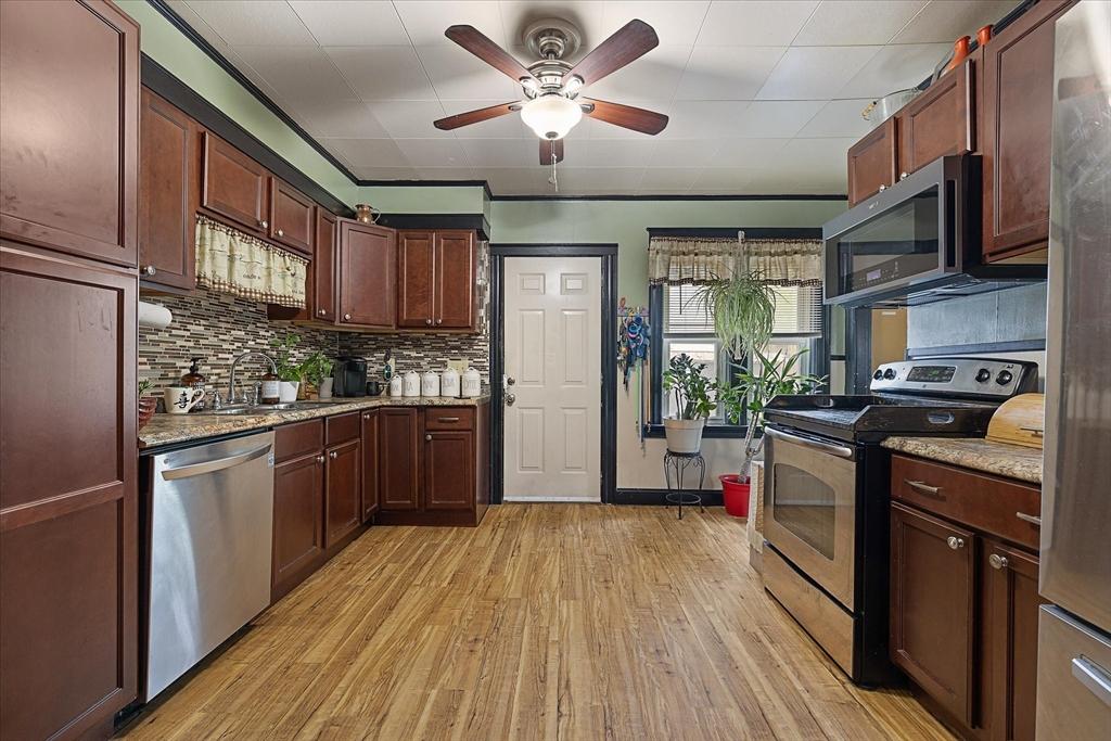 85 Pinehurst Ave, Auburn, MA 01501 - kitchen featuring stainless steel appliances, a sink, light wood-style flooring, a ceiling fan, and decorative backsplash