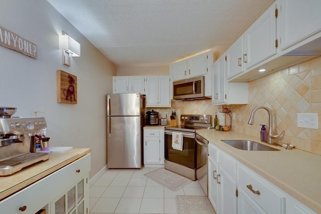 289 Elm St Unit 34B, Medford, MA 02155 - kitchen with stainless steel appliances, a textured ceiling, tasteful backsplash, white cabinets, and light tile patterned flooring
