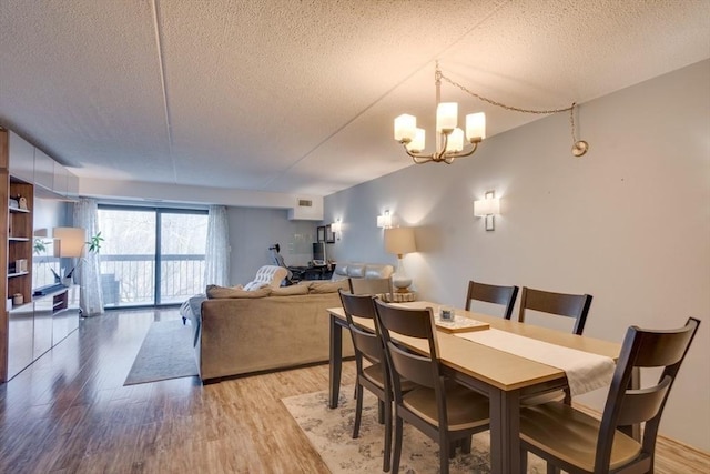 289 Elm St Unit 34B, Medford, MA 02155 - dining space featuring a textured ceiling, light wood finished floors, and a chandelier