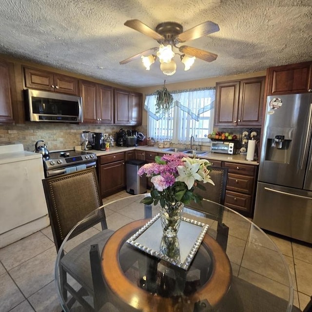 kitchen featuring tasteful backsplash, appliances with stainless steel finishes, light countertops, a sink, and light tile patterned flooring