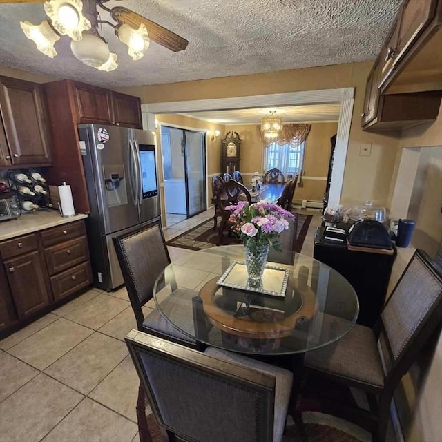 dining space with ceiling fan with notable chandelier, a textured ceiling, and light tile patterned floors