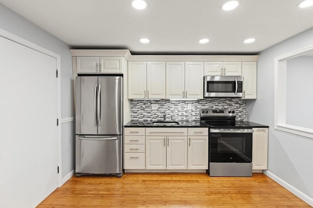 924 Main St Unit 14, Woburn, MA 01801 - kitchen featuring appliances with stainless steel finishes, dark countertops, backsplash, light wood-style floors, and recessed lighting