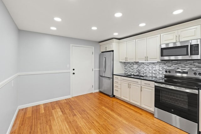 924 Main St Unit 14, Woburn, MA 01801 - kitchen featuring stainless steel appliances, a sink, light wood-style floors, decorative backsplash, and recessed lighting