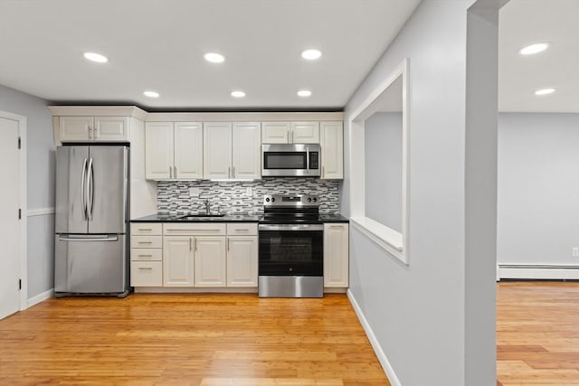 924 Main St Unit 14, Woburn, MA 01801 - kitchen featuring stainless steel appliances, a sink, backsplash, light wood-type flooring, and a baseboard radiator