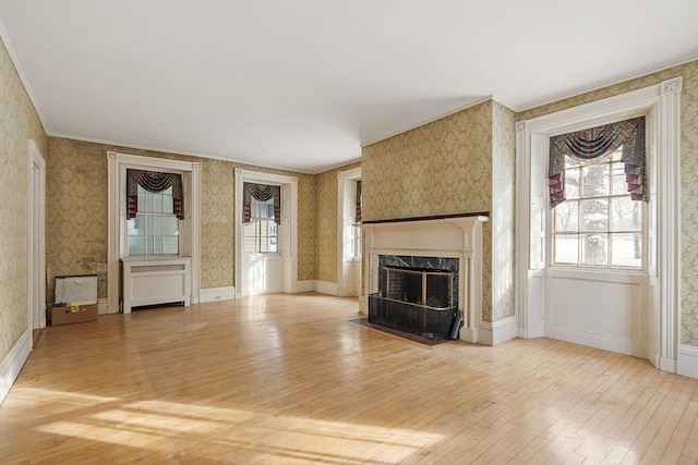 unfurnished living room featuring a premium fireplace, ornamental molding, radiator heating unit, and light hardwood / wood-style flooring