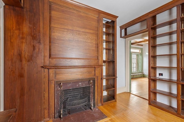 unfurnished living room featuring a baseboard radiator and light wood-type flooring