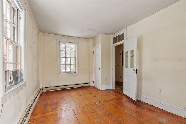 unfurnished room featuring a baseboard heating unit and hardwood / wood-style floors