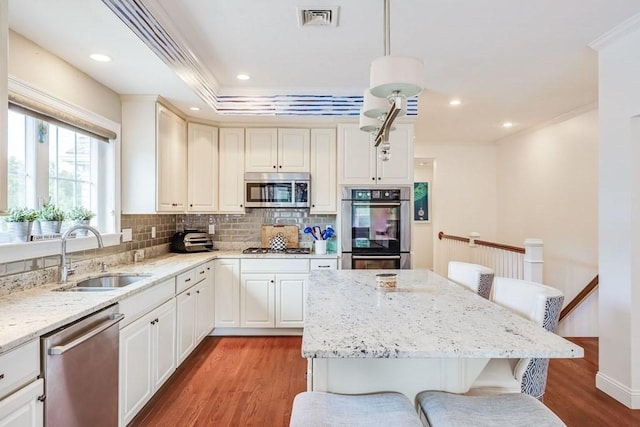 kitchen with hardwood / wood-style floors, sink, decorative light fixtures, a kitchen bar, and stainless steel appliances