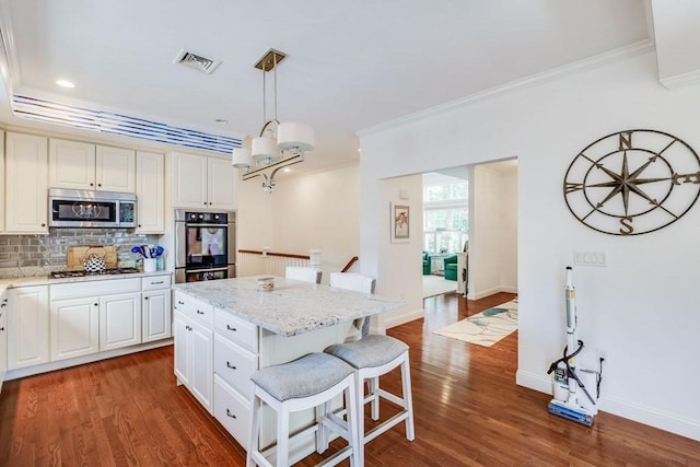 kitchen featuring a center island, dark wood-type flooring, stainless steel appliances, decorative light fixtures, and a kitchen bar