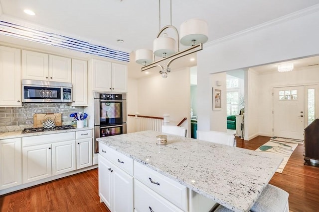 kitchen featuring pendant lighting, a breakfast bar, a center island, crown molding, and appliances with stainless steel finishes