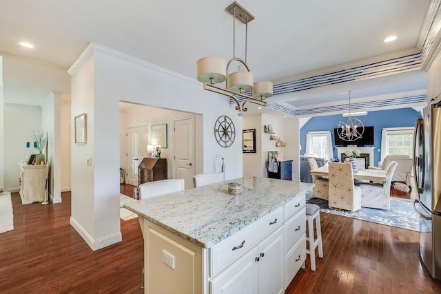 kitchen with stainless steel refrigerator, dark wood-type flooring, a kitchen island, pendant lighting, and white cabinets