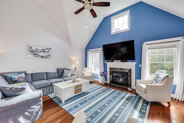 living room with ceiling fan, a fireplace, high vaulted ceiling, and wood-type flooring