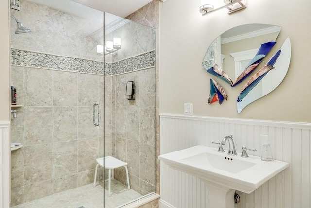 bathroom featuring sink, a shower with shower door, and crown molding