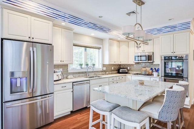 kitchen with a center island, dark wood-type flooring, sink, decorative light fixtures, and stainless steel appliances