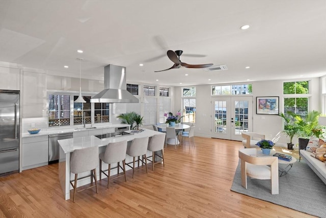 142 Amory St Unit 2, Cambridge, MA 02139 - kitchen with a center island, stainless steel appliances, a kitchen breakfast bar, range hood, and white cabinetry