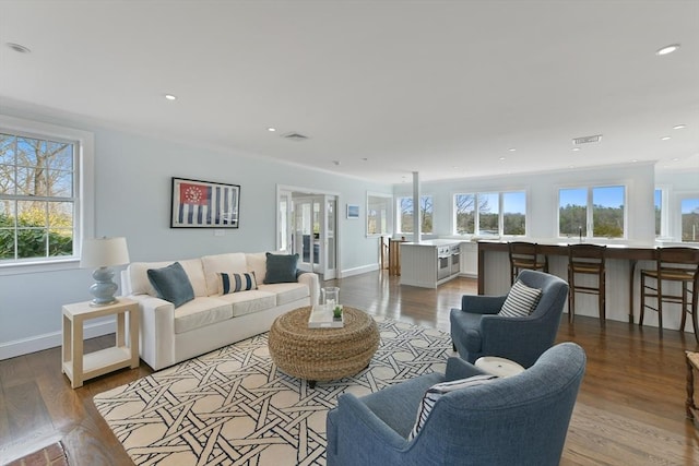 living area with recessed lighting, visible vents, baseboards, and wood finished floors
