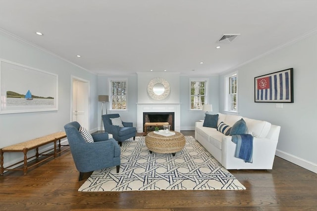 living area featuring visible vents, wood finished floors, a fireplace, and ornamental molding