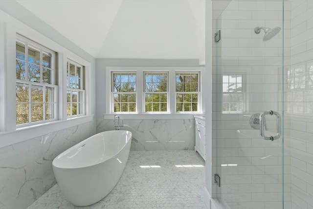 bathroom with a freestanding bath, tile walls, a shower stall, and vaulted ceiling