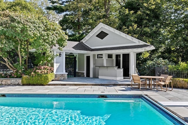 outdoor pool featuring outdoor dry bar, a storage structure, fence, an outdoor structure, and a patio area