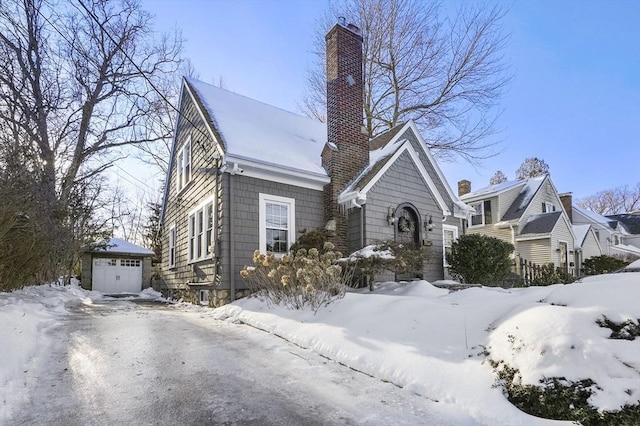 view of front of property featuring an outdoor structure, a chimney, and a detached garage