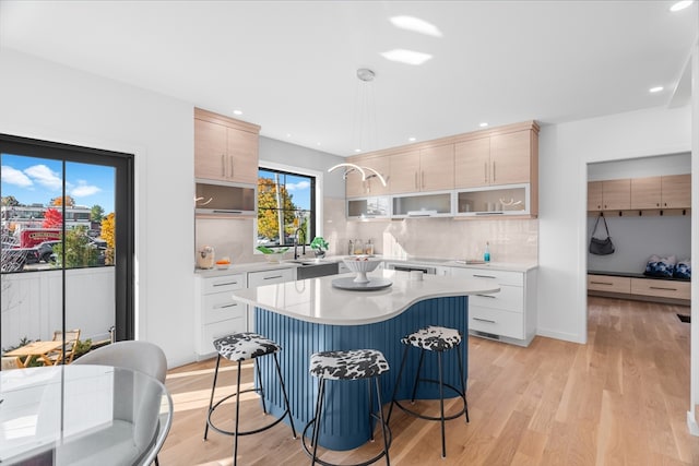 kitchen featuring white cabinetry, light hardwood / wood-style floors, a breakfast bar, and a kitchen island