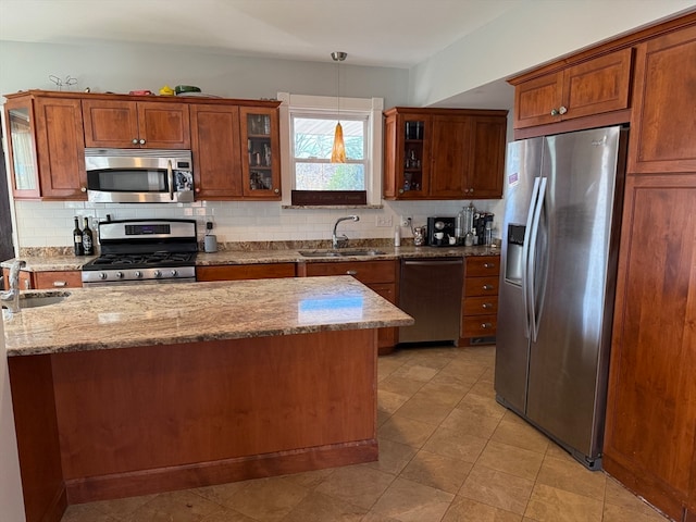 kitchen with sink, light stone countertops, stainless steel appliances, and hanging light fixtures