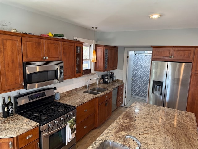 kitchen with tasteful backsplash, light stone counters, stainless steel appliances, sink, and hanging light fixtures