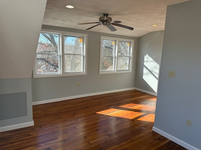 spare room with vaulted ceiling, plenty of natural light, dark wood-type flooring, and ceiling fan