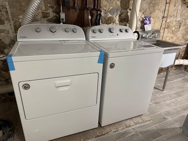 clothes washing area with washing machine and clothes dryer and hardwood / wood-style flooring