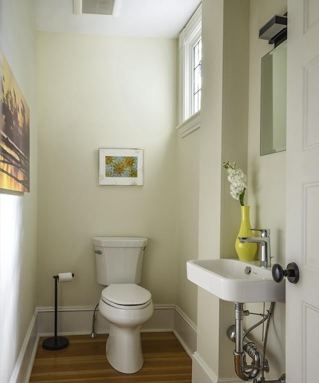 bathroom featuring baseboards, wood finished floors, visible vents, and toilet
