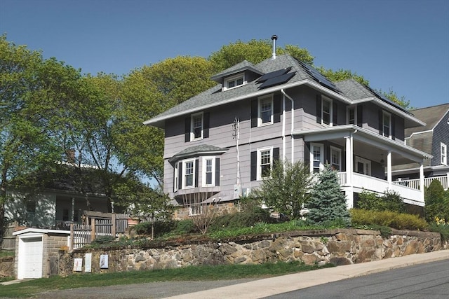 view of home's exterior with a porch, a garage, and roof mounted solar panels