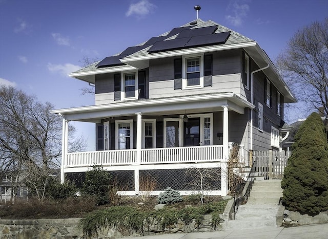 american foursquare style home with a porch and roof mounted solar panels
