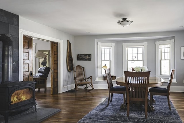 dining area with baseboards, a wood stove, and wood finished floors