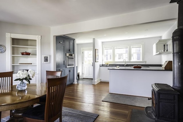 dining area with a healthy amount of sunlight, a wood stove, and dark wood-type flooring