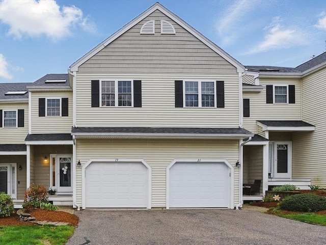 view of property featuring asphalt driveway and an attached garage