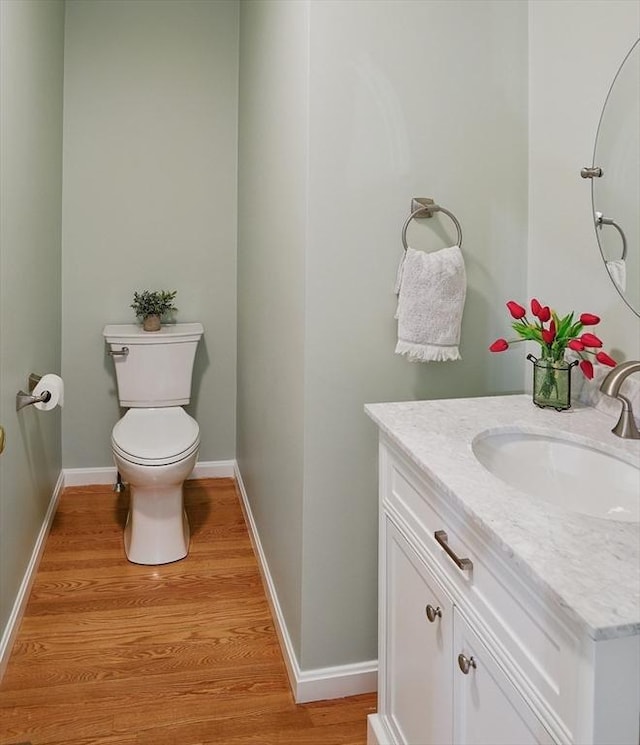 bathroom featuring wood finished floors, vanity, baseboards, and toilet