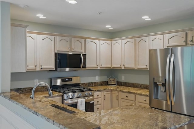 kitchen with appliances with stainless steel finishes, stone counters, recessed lighting, a peninsula, and a sink