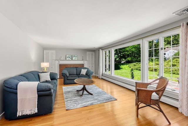 64 Bakers Hill Rd, Weston, MA 02493 - living room featuring a baseboard radiator, plenty of natural light, wood finished floors, and a brick fireplace
