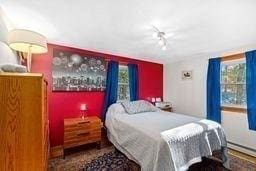 bedroom with a baseboard radiator and rail lighting