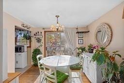 dining area with light wood-type flooring and an inviting chandelier