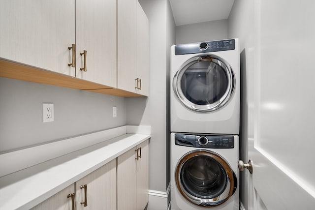 laundry area with cabinets and stacked washing maching and dryer