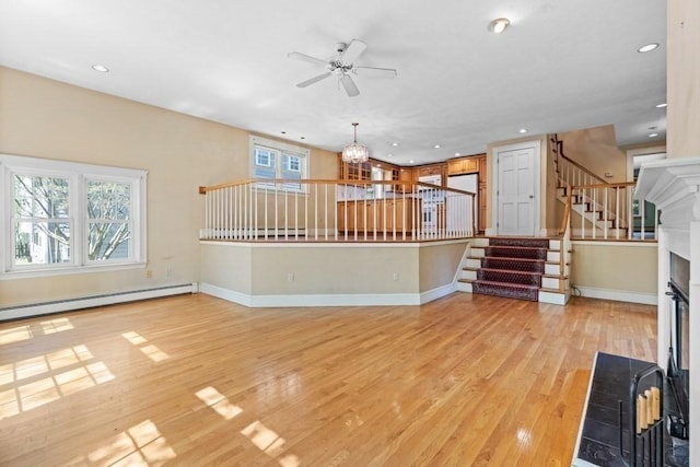 unfurnished living room featuring stairs, ceiling fan, light wood-type flooring, recessed lighting, and a baseboard heating unit