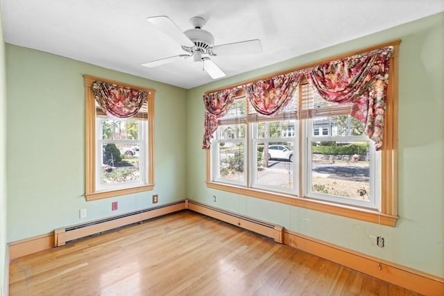 unfurnished room with a ceiling fan, baseboards, a baseboard heating unit, and wood finished floors