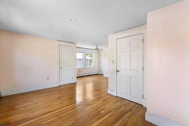 unfurnished room with light wood-type flooring, baseboards, ceiling fan, and baseboard heating