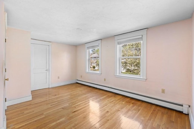 unfurnished bedroom with baseboards, baseboard heating, and light wood-style flooring