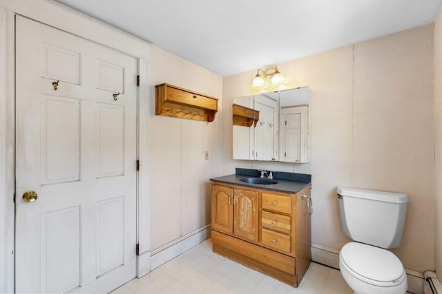 bathroom featuring vanity, baseboards, a baseboard heating unit, and toilet