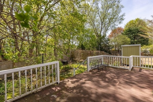 deck featuring an outbuilding, a fenced backyard, and a shed
